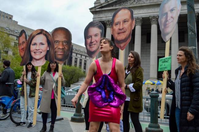 Molly Gaebe (center) invited protesters to channel their rage toward cutouts of six Supreme Court justices’ heads. Photo: Abigail Gruskin