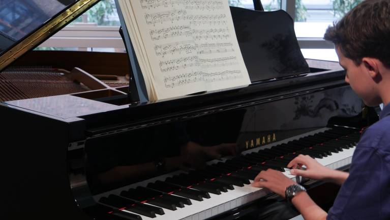 Teen practices piano at Le Maison school of music.