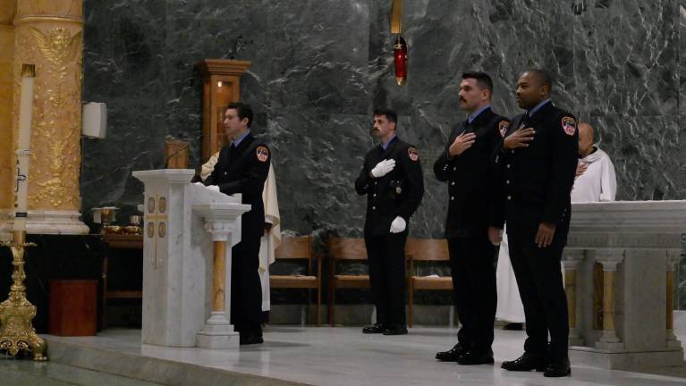 Firefighters, hands over hearts, during mass at St. Francis of Assisi, Sept. 11, 2025.