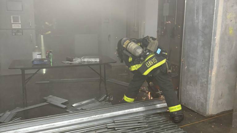 Firefighter cuts through metal gate to access source of fire about a half mile below street level in the Grand Central Madison station.