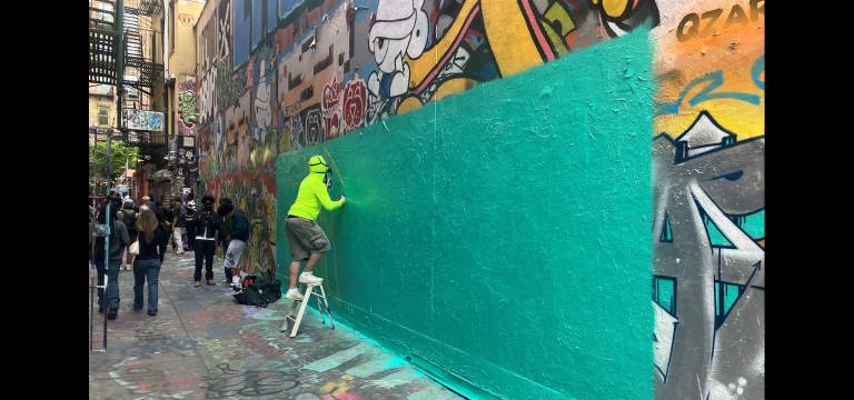 Freeman Alley is a living art space, continuously regenerating. Here a graffiti artist prepares the canvas for a new iteration.