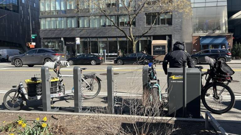 A delivery worker, who wanted to remain unnamed charging his e-bike at the Swiftmile charging station on March 11 at Cooper Square in the East Village. Photo Credit: Alessia Girardin.