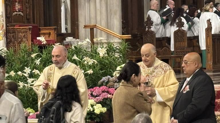 Msgr. Joseph LaMorte (gold vestments, right), giving out communion at St. Patrick’s Cathedral, said Cardinal Dolan will be back in NYC next week and will tell what he can about the conclave that elected Pope Leo XIV.